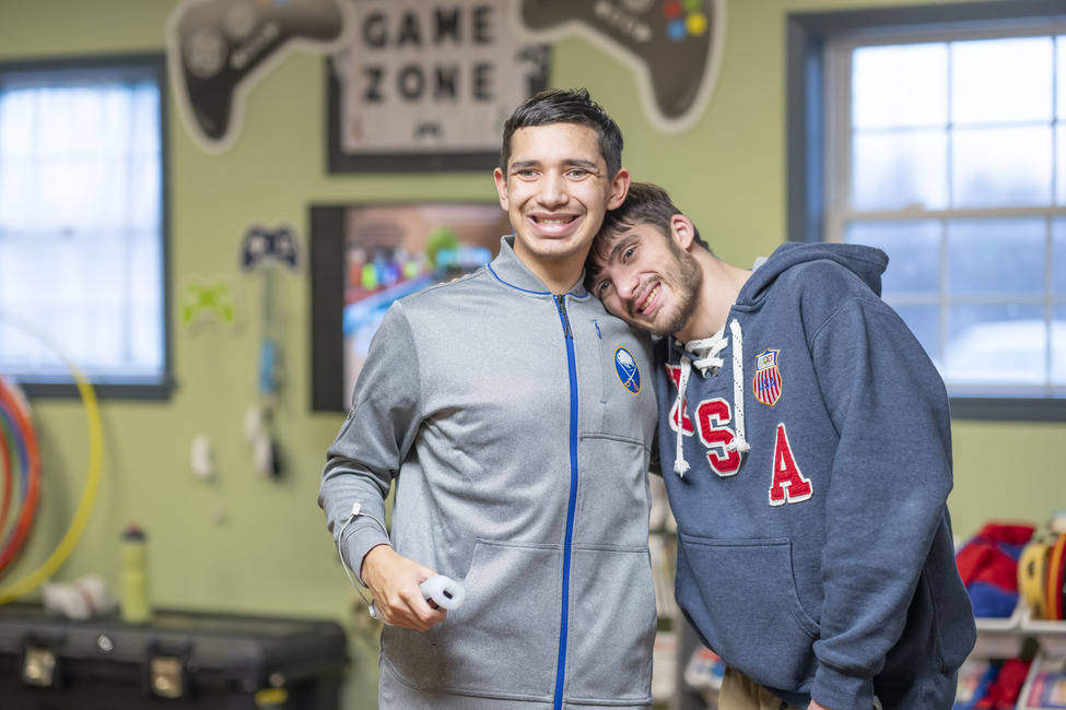 Support Make a difference in the lives of people with special needs. Two young men smile and pose while playing a video game at People Inc. Respite.