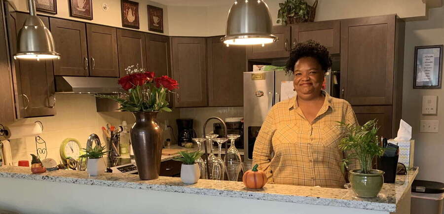 Black woman smiling in her apartment kitchen